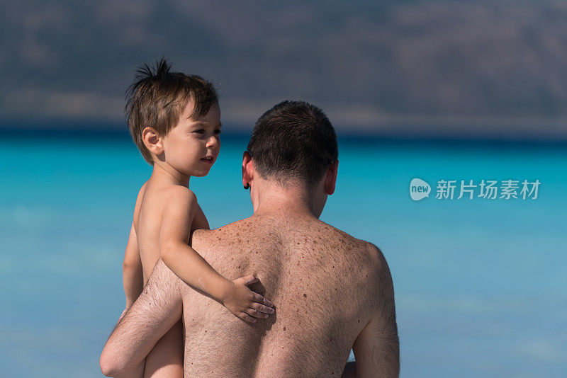 快乐的父亲拥抱儿子，在海上玩耍