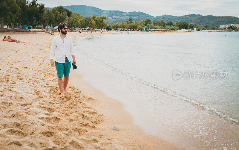 一个留着胡子的年轻人在海滩上散步