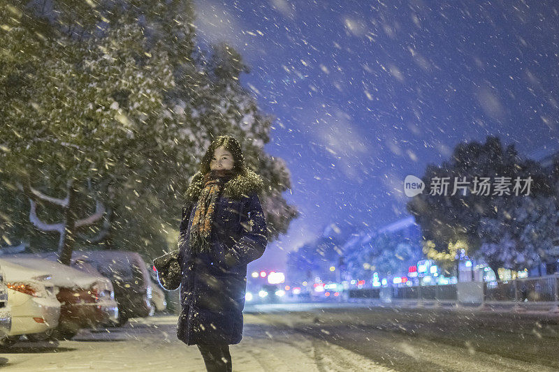 美丽的女人站在雪地里的街道上