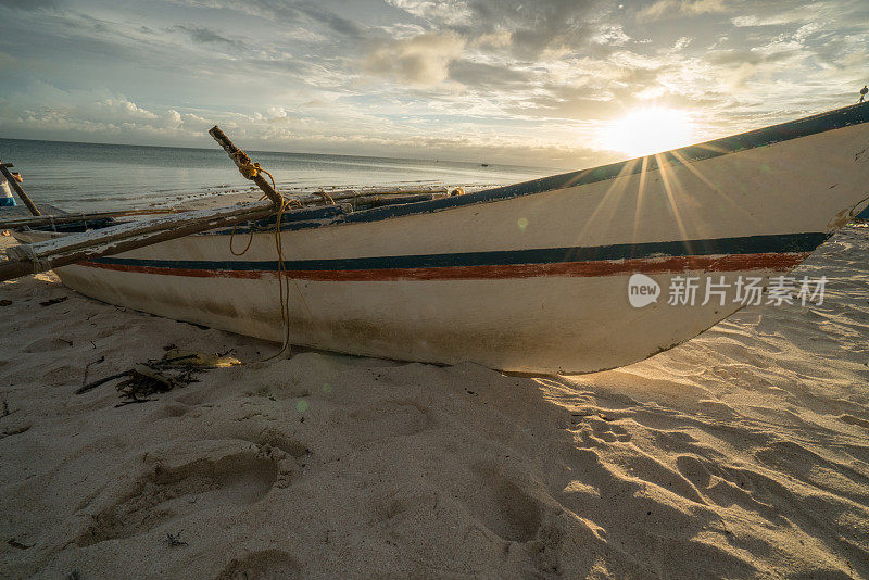 日落时分，菲律宾热带海滩上的渔船