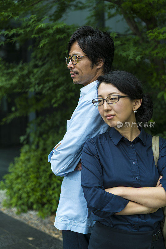 日本京都，一名中年女商人和一名戴眼镜的女商人，在建筑物前相互倚靠。