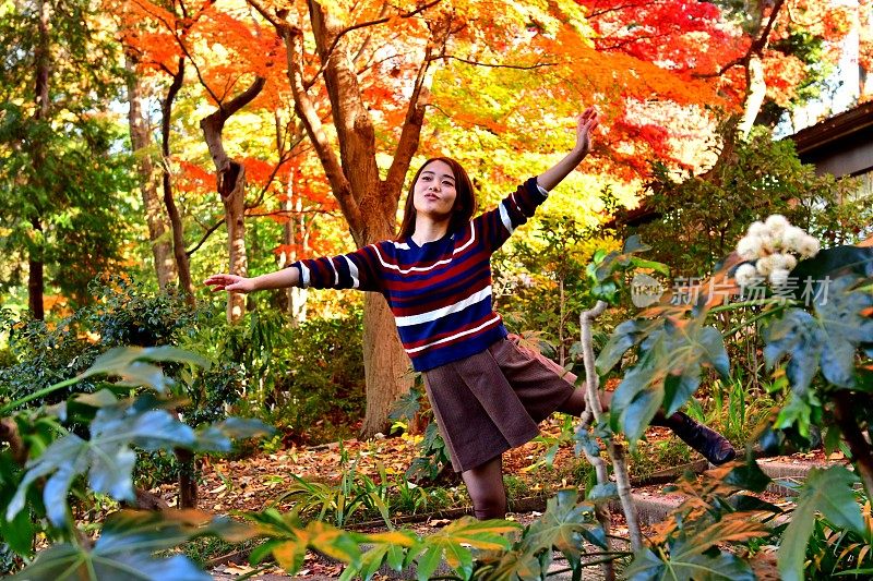 年轻的日本女人站在美丽的秋叶下锻炼，东京