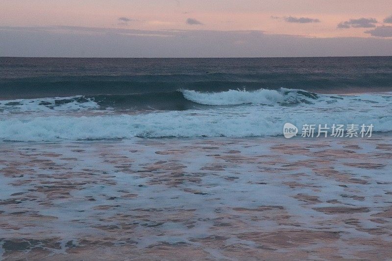 日出时海浪涌上海滩