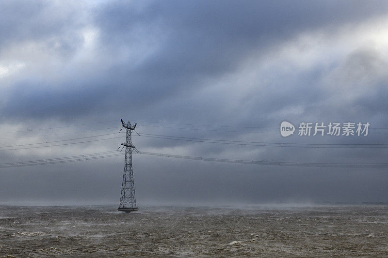 海上电力塔在暴风雨中与大浪袭击海岸