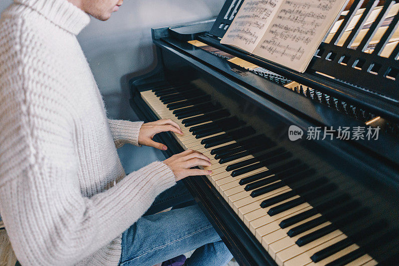 穿毛衣的男人在家里弹钢琴