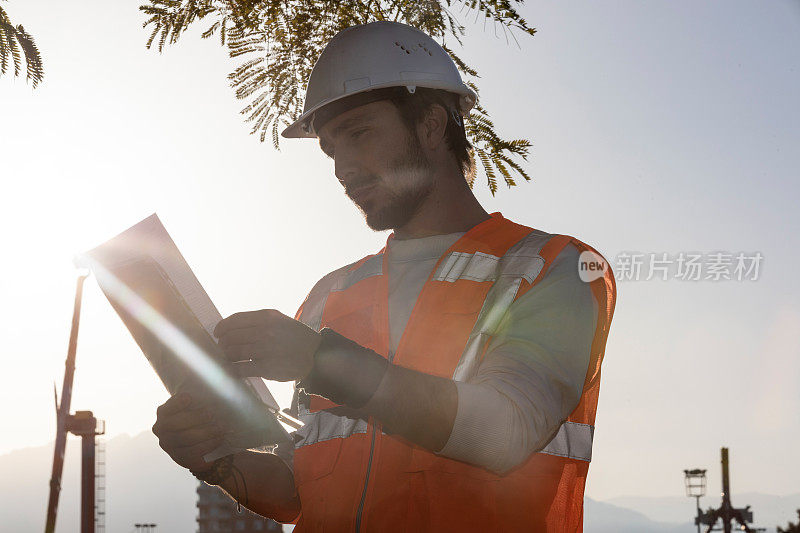 建筑工程师在建筑场地控制数据表和戴安全帽