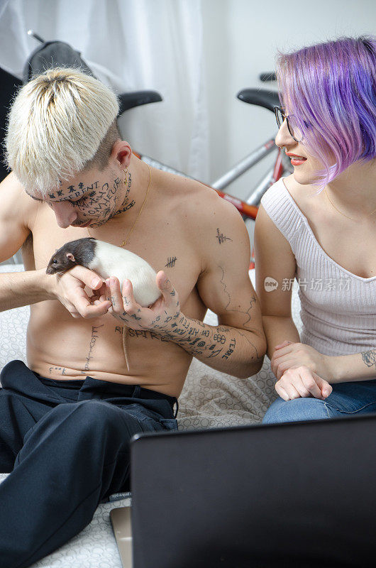年轻的纹身夫妇在家里玩宠物老鼠