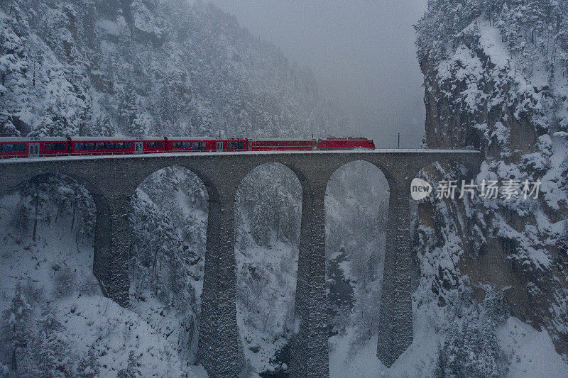 红色火车冰川在瑞士Landwasserviadukt上方的暴风雪中外露