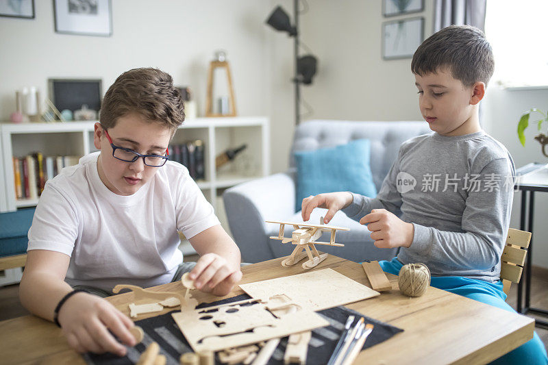 兄弟们正在为学校项目制作木制模型飞机