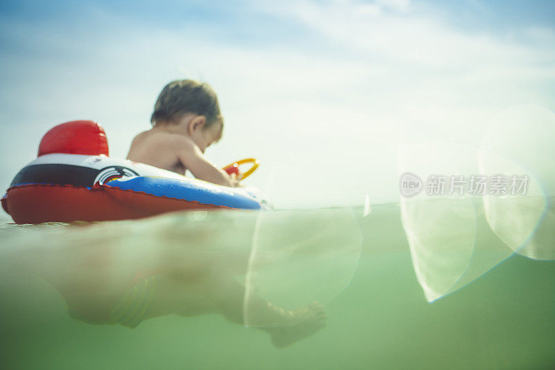 通过海浪散焦的照片，一个小男孩在海上的充气筏