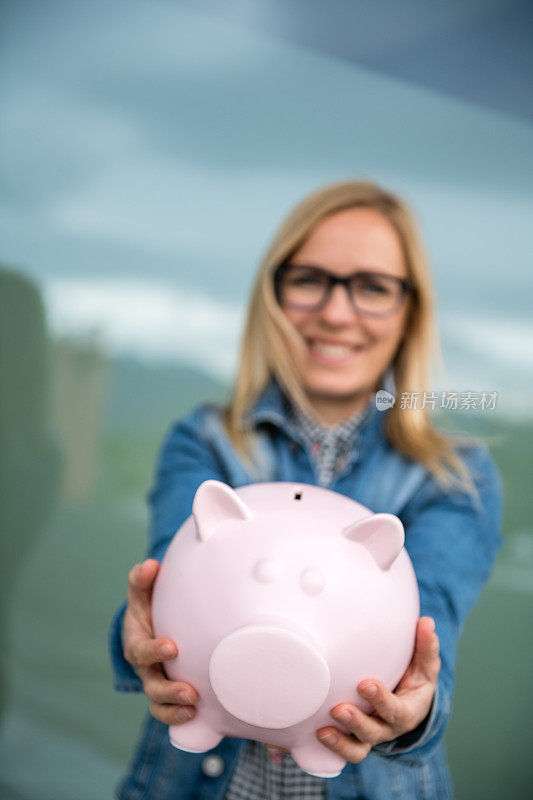 年轻的成年女子抱着存钱罐。存钱和投资