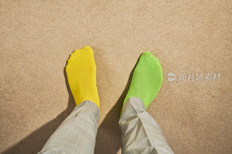 POV的观点，男人的脚穿着奇怪的袜子，黄色和绿色。