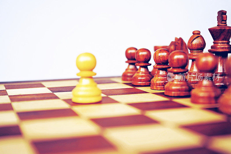 在一盘国际象棋中，一个白色的棋子面对着另一组黑褐色的棋子