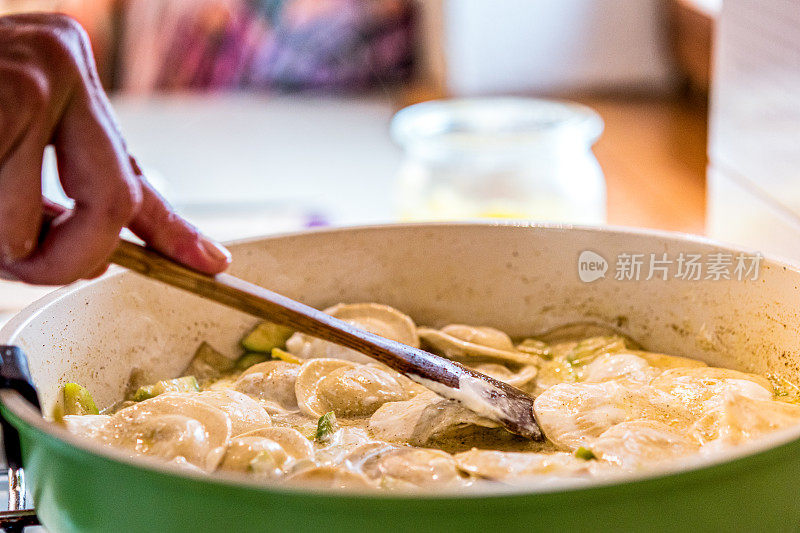 近距离女人的手煎饺子与西葫芦和戈贡佐拉奶酪