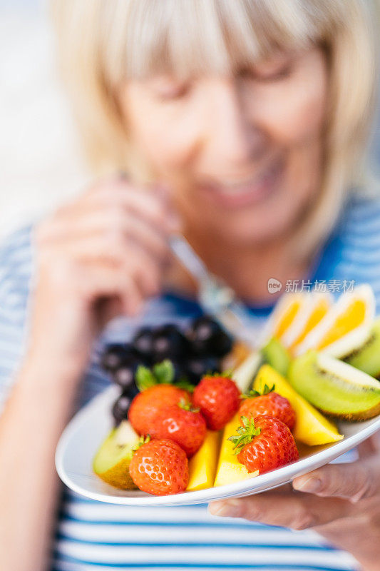 迷人的资深女士和水果午餐