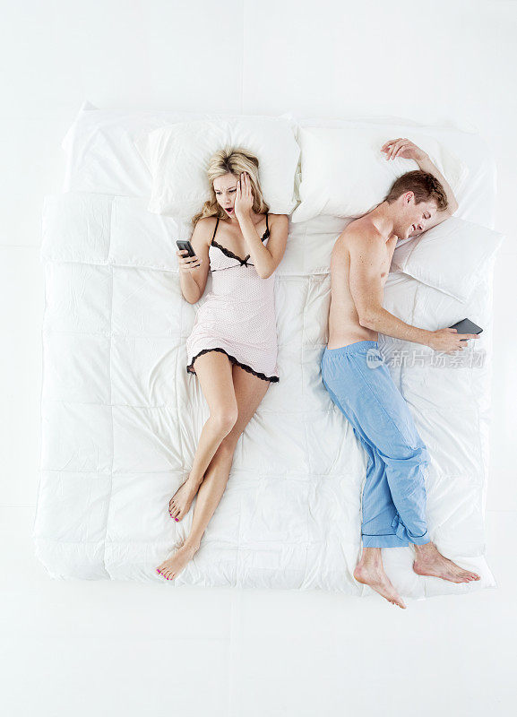 男朋友穿着睡衣躺在卧室的白色背景下，用着触摸屏