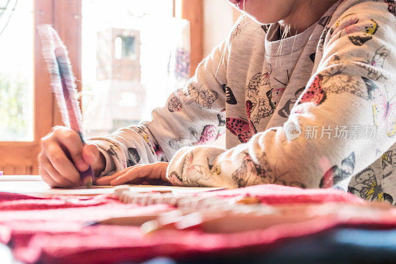 女学生坐在餐桌前用彩色铅笔画画