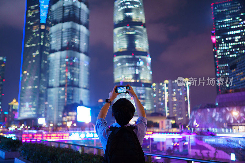年轻的亚洲男子用智能手机拍照