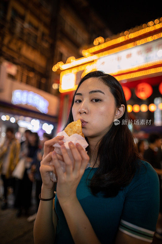 年轻女子在夜市吃街头小吃