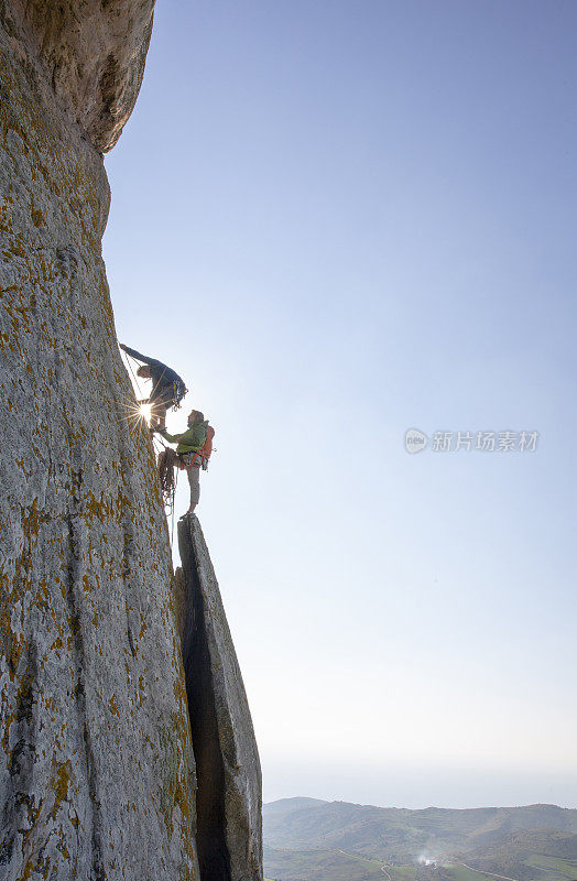 登山者在日出时攀登岩面