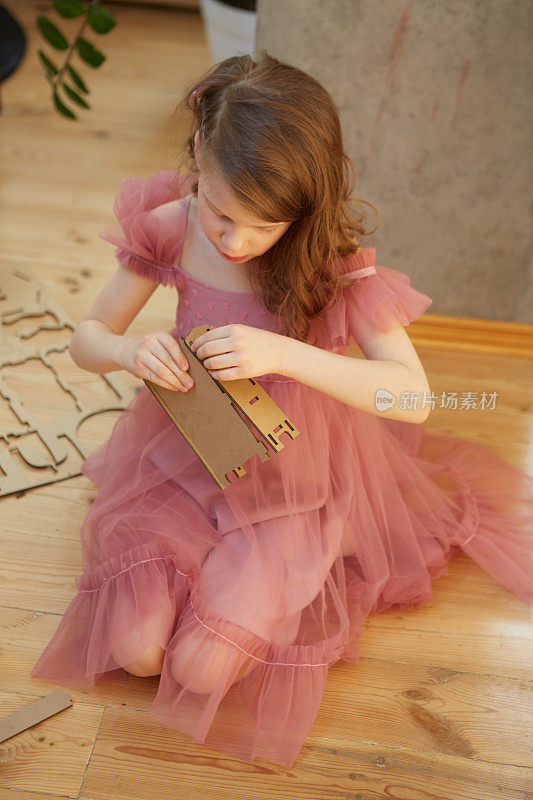 一个女孩玩纸板玩具玩具屋家具。