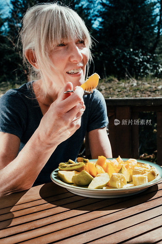 一位老妇人在院子里吃水果午餐