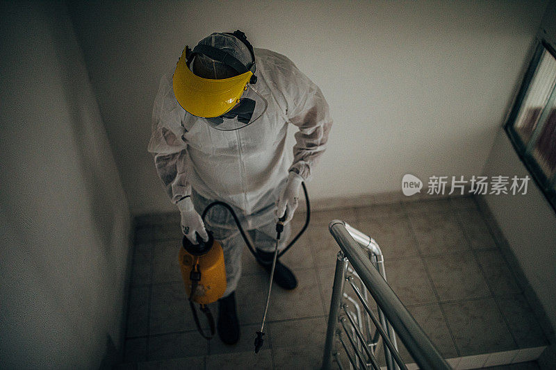 穿着防护服的人在建筑物中消毒步骤