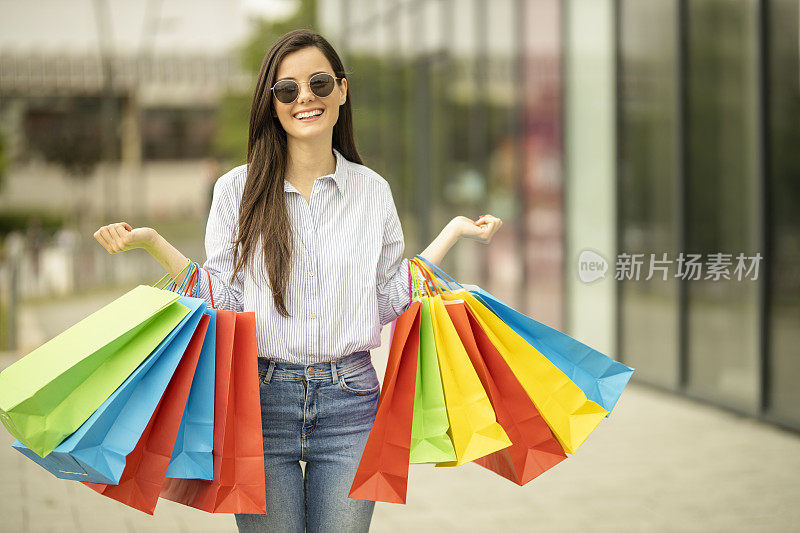 快乐的女人拿着购物袋在购物中心享受购物