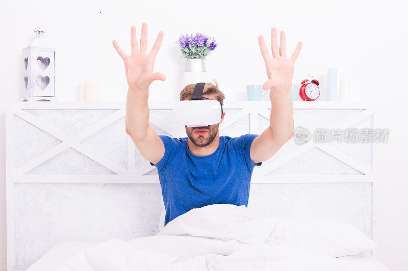 最好的VR体验。帅哥戴着VR头戴在床上。白人在卧室里戴着VR眼镜。VR中的沉浸式渲染