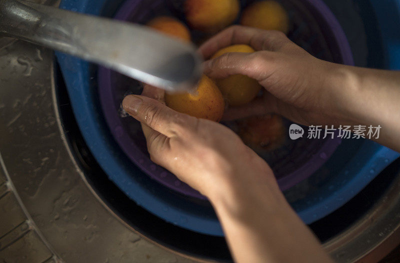 女人的手在水里洗两个杏子