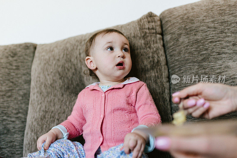 小女孩坐在沙发上吃饭