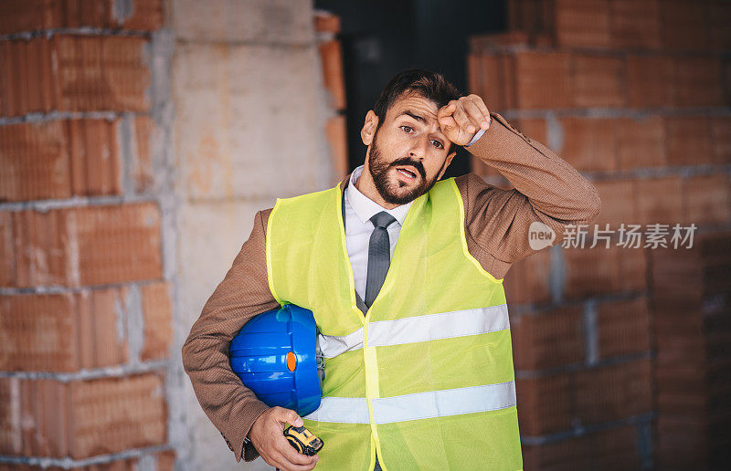 疲惫的建筑工人在工地擦拭额头。