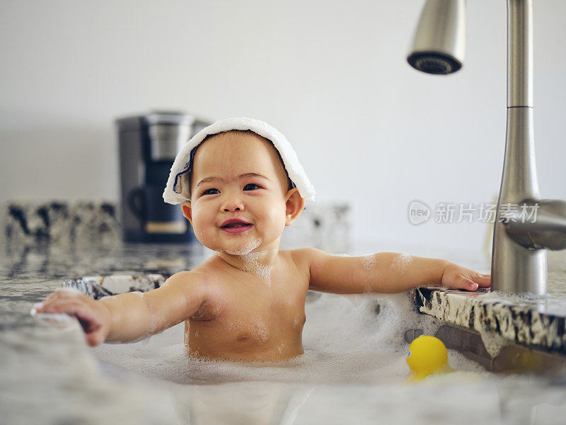 婴儿在厨房水槽洗澡