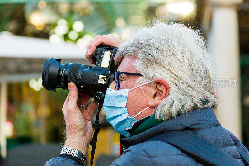 高级男摄影师戴着防护口罩在城市里