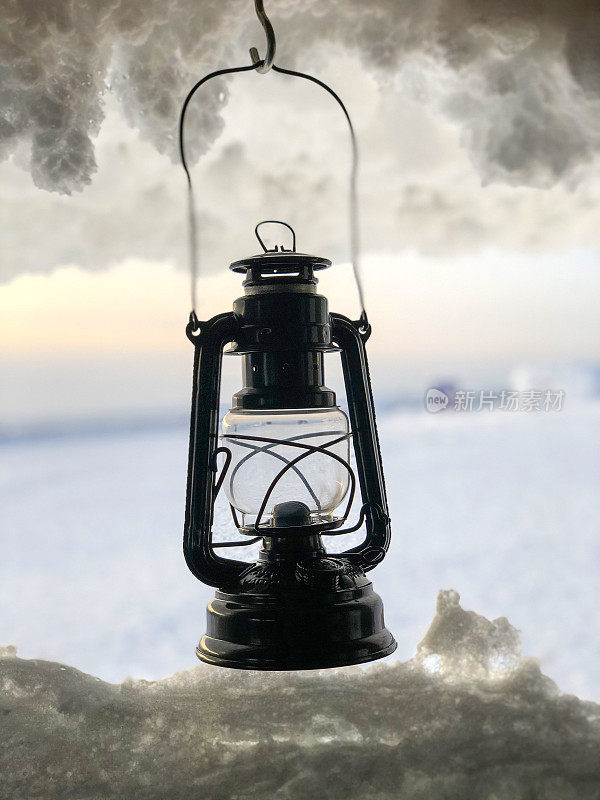 室外的老式煤油灯，背景是雪。