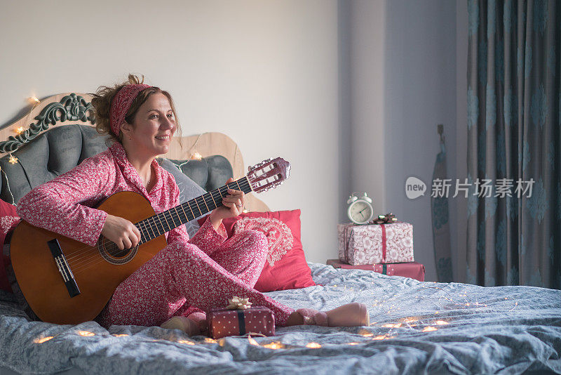 圣诞节的时候，一个女人在床上弹吉他。