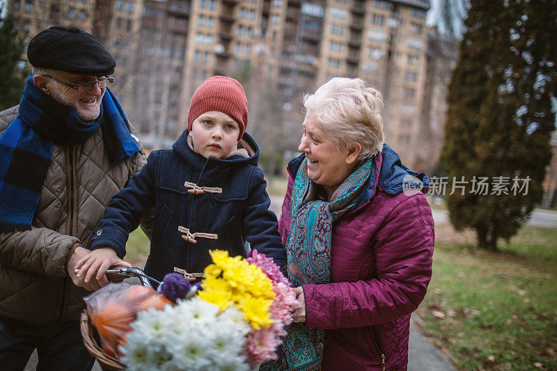 活跃的老夫妇和孙子在户外骑自行车散步。