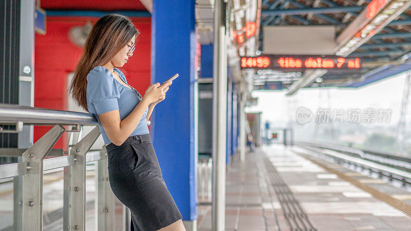 亚洲妇女用电话等火车