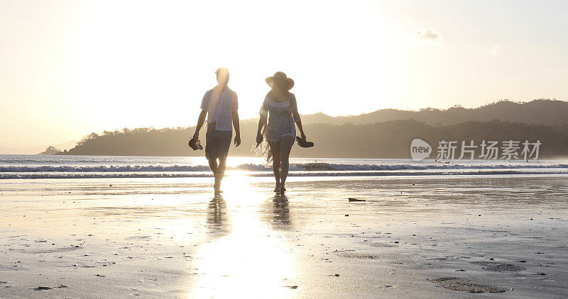 日出时分，一对成熟的夫妇在沙滩上散步