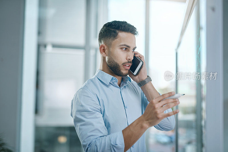 这是一个年轻的商人在现代办公室里用智能手机进行头脑风暴的照片
