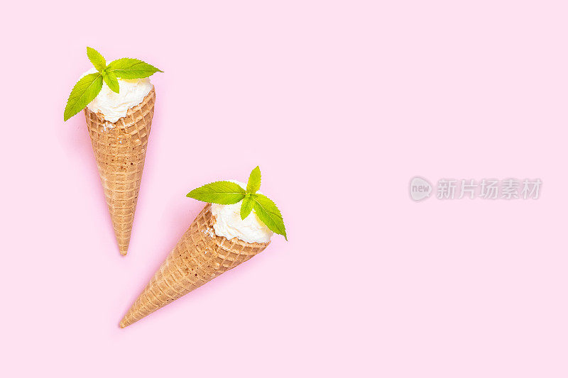 两个香草冰淇淋蛋筒，粉红色背景上有薄荷。副本的空间。最小的夏天背景。