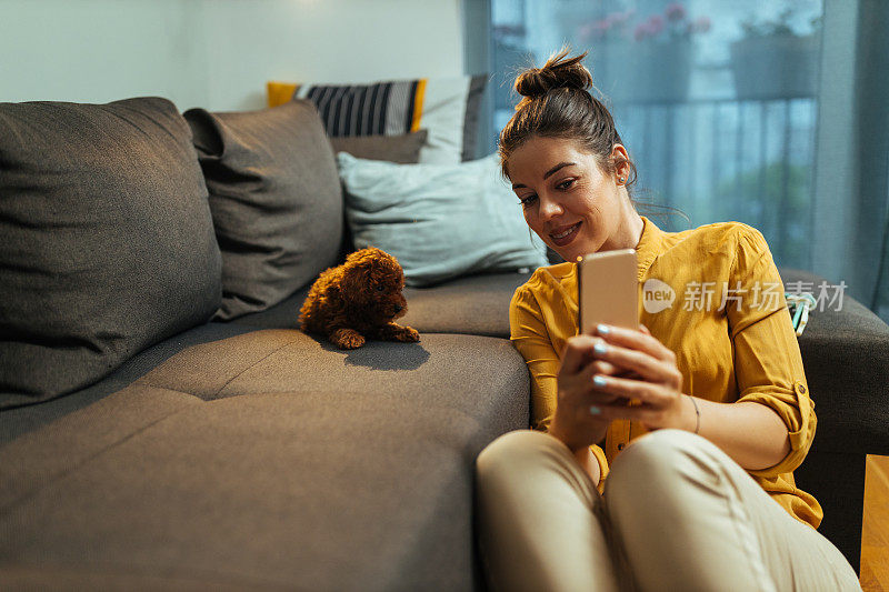 一个女人和她可爱的小狗一起用手机