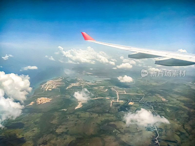 在古巴上空，用飞机的翅膀从云层上俯瞰哈瓦那市(在美丽的风景和云景的乡村旅行)。