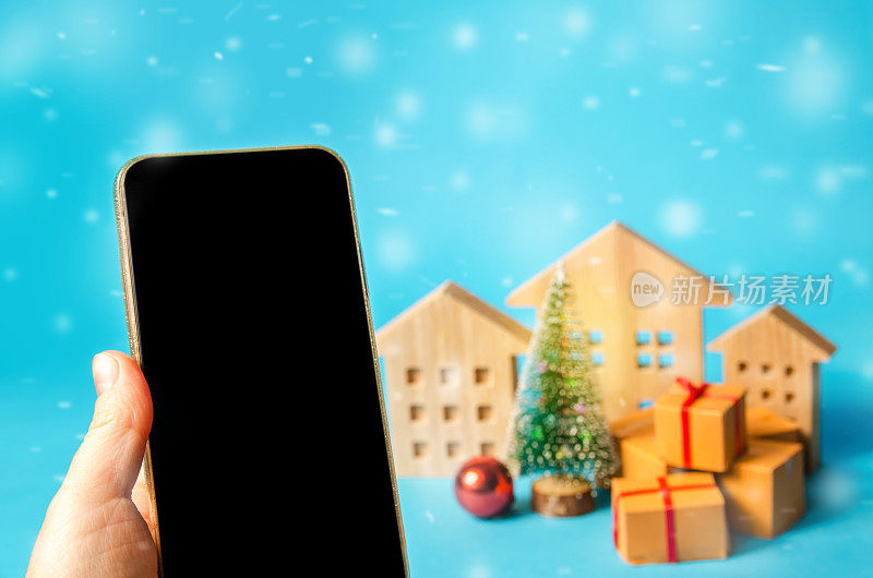 手机与空白屏幕和地方的文字，圣诞树，房子和礼物。网上购物的概念。假日销售和促销。圣诞快乐，恭贺新禧