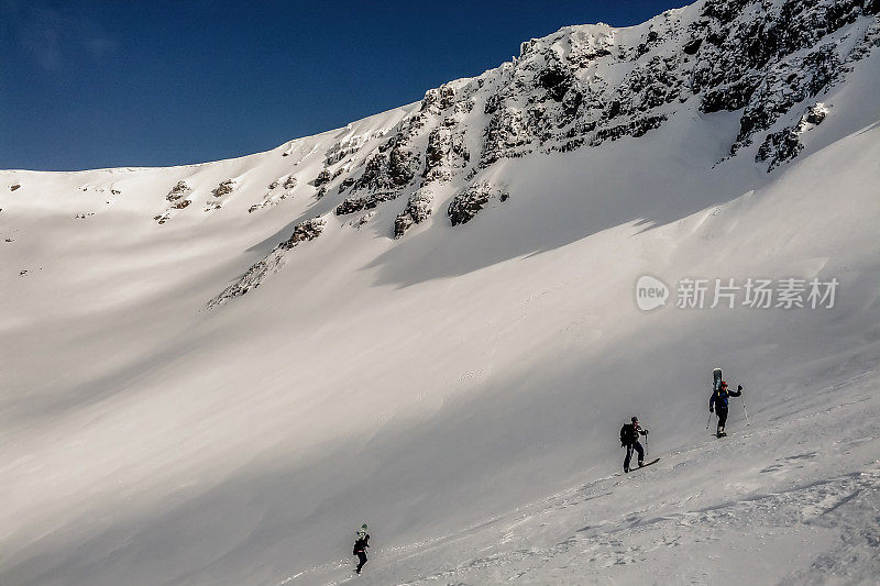 白雪覆盖的陡峭山峰和登山者滑雪的全景