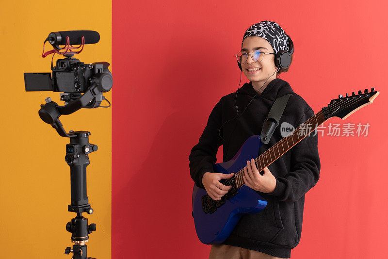 一名年轻的视频博主在摄影棚里在线教弹吉他