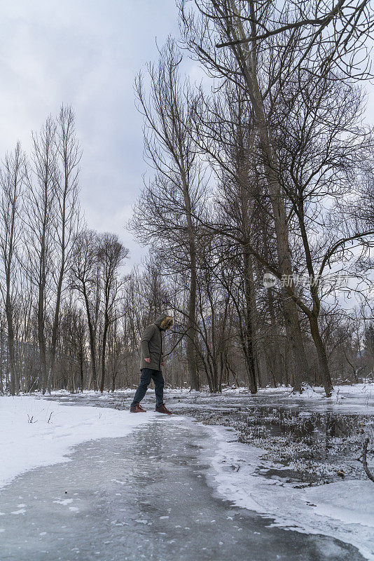 人类走过冰冷的小溪和雪景的图像