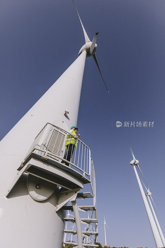 年轻的女工程师正在现场检查风力涡轮机