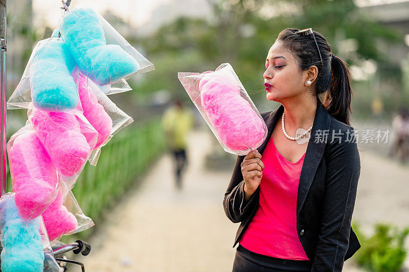 可爱的女人吃棉花糖在游乐场