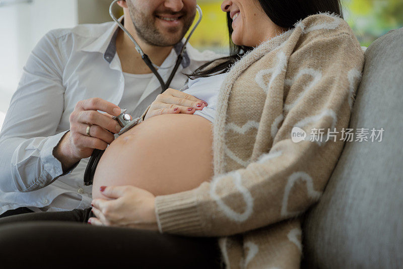 男人用听诊器在他怀孕妻子的肚子上听婴儿的心跳